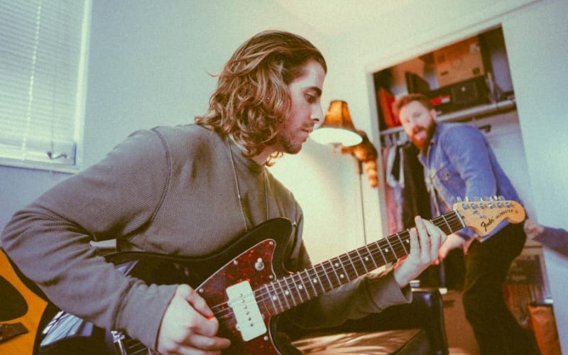 musician playing guitar in bedroom studio setup