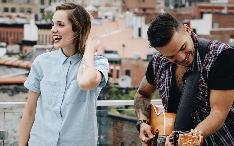 Man and woman, topline writers singing outside with a guitar