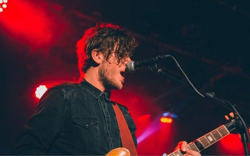 man singing with guitar on stage