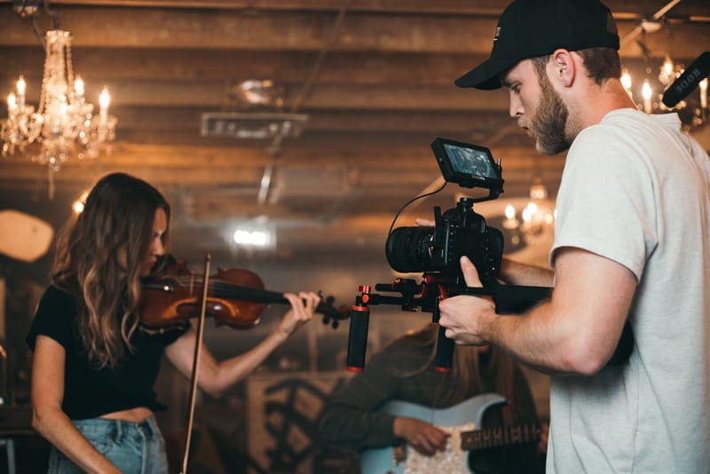 man-holding-camera-and-woman-playing-violin