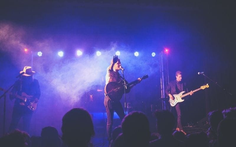 Man on stage with a guitar singing might be wondering how to become a music publisher