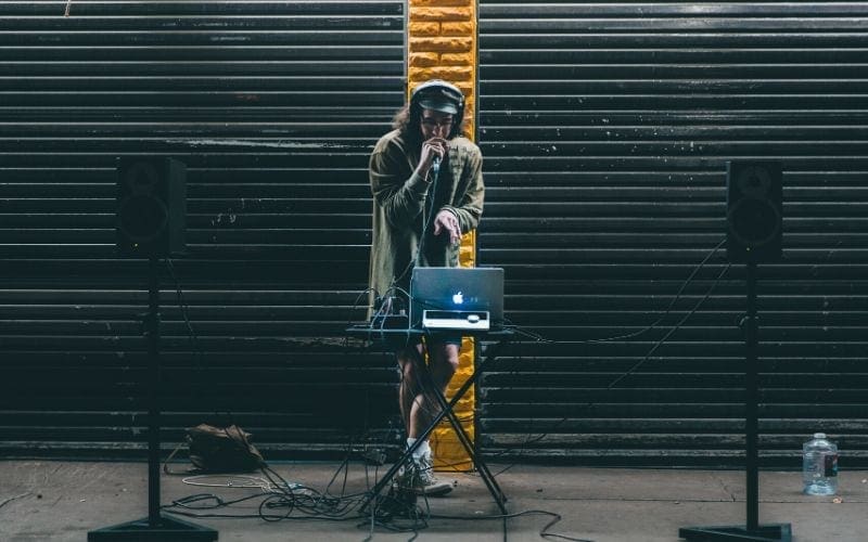 Man with laptop and microphone and speakers on a black and yellow backdrop