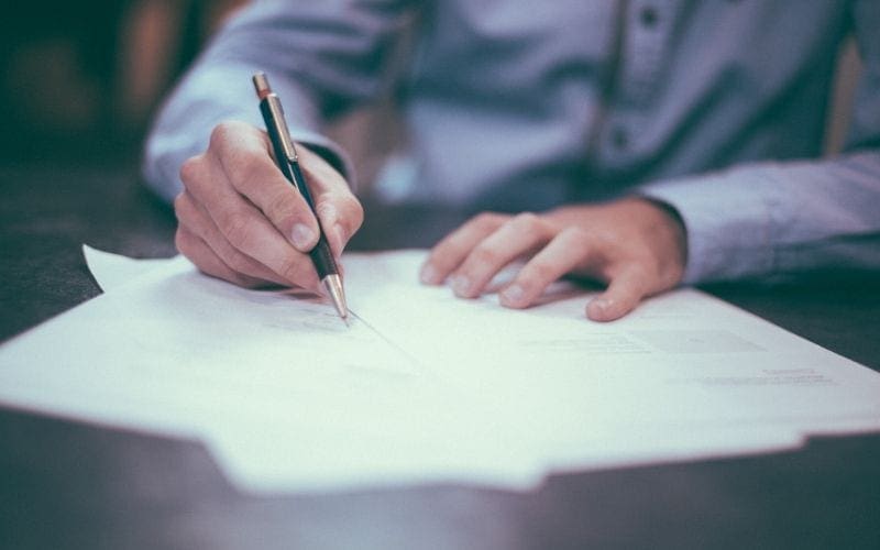 Man signing a contract with a pen in a suit to become a music publisher