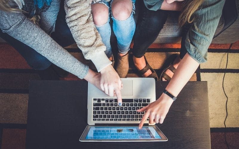 Three women pointing at laptop screen making an EPK